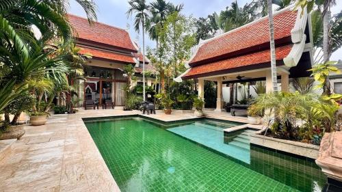a house with a swimming pool in front of a house at Luxury Balinese Pool Villa in Na Jomtien