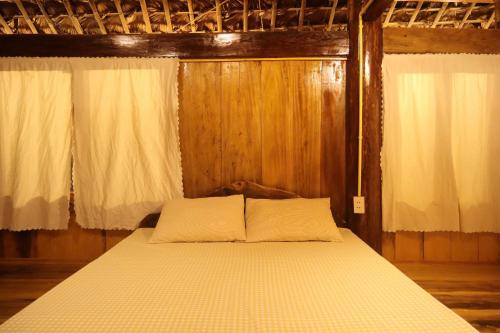a bed with two pillows in a wooden room at little Island in Na Lúng