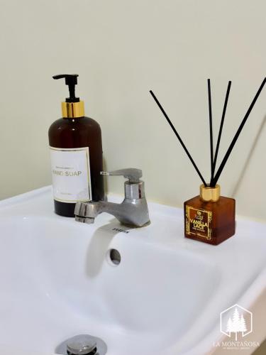 a bottle of soap sitting on a bathroom sink at Solace - 1BR Brenthill Condo with Balcony Near Session and SM in Baguio