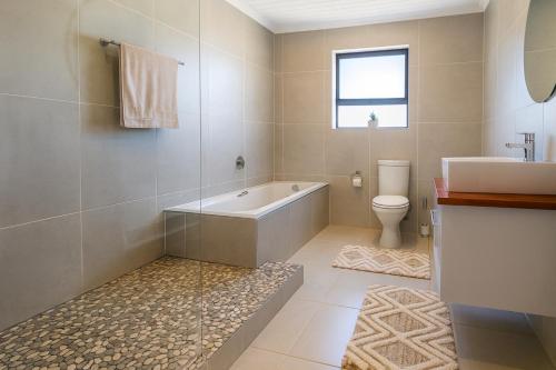 a bathroom with a tub and a toilet and a sink at Van Temp Beach House in Britannia Bay