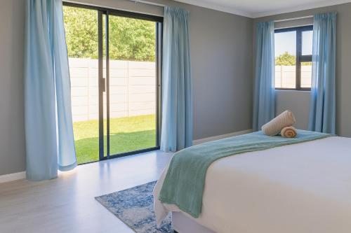 a bedroom with a bed and a large window at Van Temp Beach House in Britannia Bay