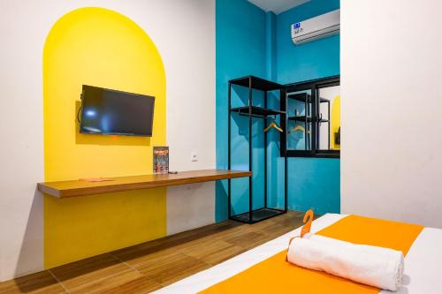 a room with a bed and a tv on a wall at Sans Salmas Mojokerto in Kranggan