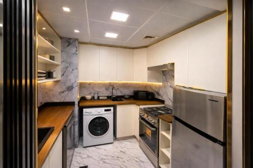 a kitchen with white cabinets and a washer and dryer at Marjan Island Beautiful Apartment Sea Side View Beach Luxury Rooms Ras Al Khaimah UAE in Ras al Khaimah