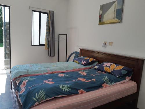 a bed with a blue comforter and two pillows at Siril Guesthouse Hostel in Nuwara Eliya