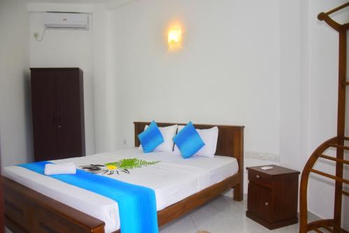 a bedroom with a bed with blue and white pillows at Ceylon Relax Villa in Aluthgama