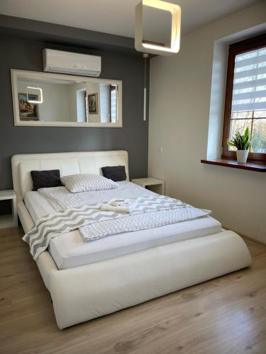 a large white bed in a bedroom with a mirror at Apartamenty AP 8 in Częstochowa