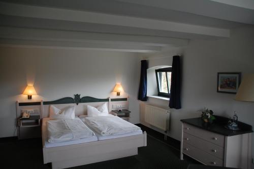 a bedroom with a bed with white sheets and a mirror at Gutshaus Redewisch Hotel & Restaurant in Boltenhagen