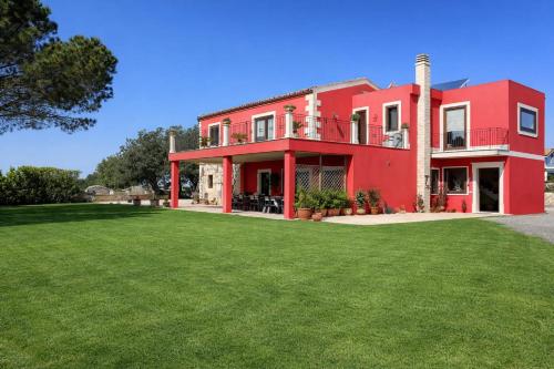 a red house with a green lawn in front of it at Richiami di Sicilia in Modica