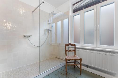 a bathroom with a shower and a wooden chair at BELETAGE in Emden