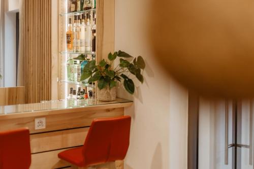 a bar with two orange chairs and a plant at Walhalla Zen Hotel Regensburg in Regensburg