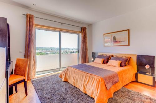 a bedroom with a bed and a large window at Vila Cantinho Algarvio Vista Rio in Ferragudo