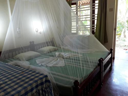 a bedroom with a bed with a mosquito net at Hector's Place in Hikkaduwa