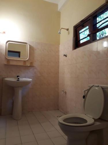 a bathroom with a toilet and a sink and a tv at Hector's Place in Hikkaduwa