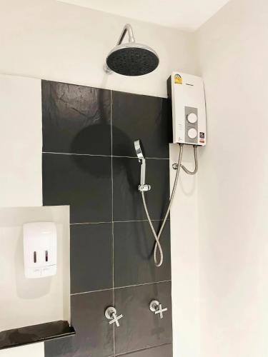 eine Dusche in einem Badezimmer mit einer Wandleuchte in der Unterkunft Phuketa Hotel Phuket Town in Phuket