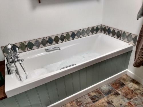 eine Badewanne in einem Badezimmer mit grün-weißen in der Unterkunft Welsh Hideaways in Pentre-briwnant