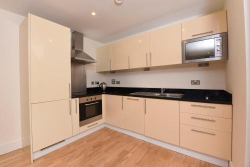 cocina con armarios blancos y microondas en RA Service Apartment, en Londres