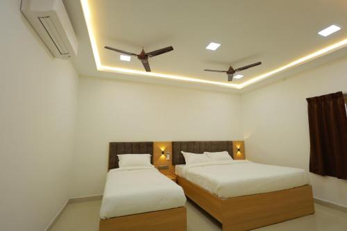 two beds in a room with two ceiling fans at ChanTini Inn in Velankanni