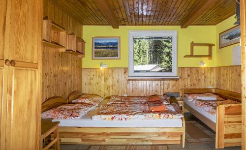 2 Betten in einem Holzzimmer mit Fenster in der Unterkunft Chaty Jasná in Demänovská Dolina