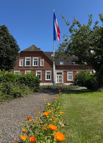 a flag in front of a house with a field of flowers at Bauernhuus 4 in Fehmarn