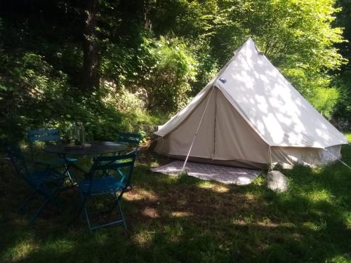 a tent in the grass with a table and chairs at Tente Tipi en plein cœur d'une forêt in Burzet