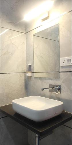 a white sink in a bathroom with a mirror at The KP RESORT in Chīrgaon