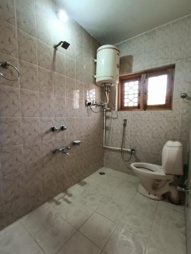 a bathroom with a shower and a toilet in it at Inayat hotel in Srinagar