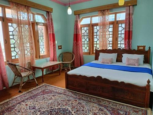 a bedroom with a bed and a table and windows at Inayat hotel in Srinagar