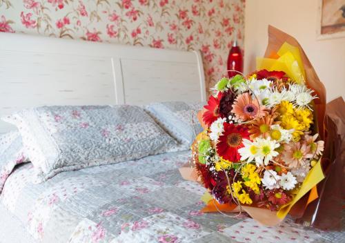 a bouquet of flowers sitting on top of a bed at Doce Canela - Pousada de Charme in Canela