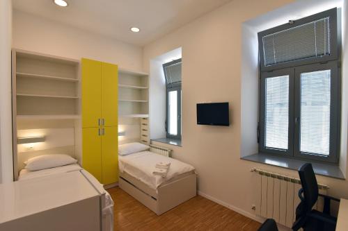 a room with two beds and a tv and two windows at SC Pula Rooms & Studio in Pula