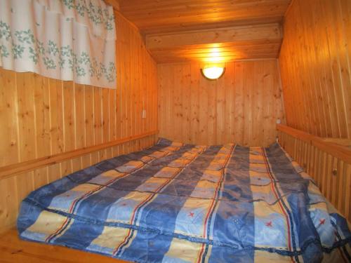 a bedroom with a bed in a wooden room at Rantakorpi Farm in Niemisjärvi