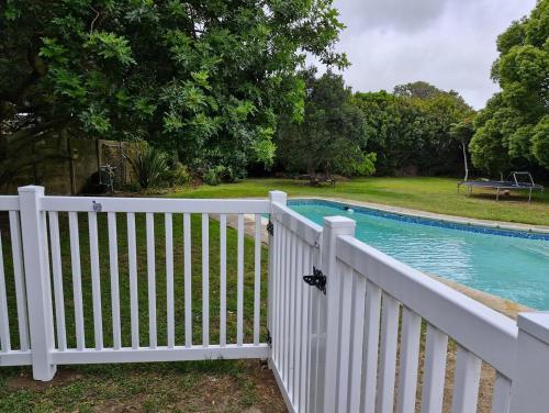 a white fence next to a swimming pool at Cosy cottage on Cassia in Gqeberha