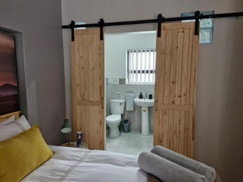 a bedroom with a bed and a bathroom with a toilet at Cosy cottage on Cassia in Gqeberha