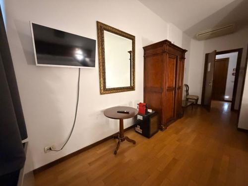 ein Zimmer mit einem Tisch und einem Fernseher an der Wand in der Unterkunft MH Hotel Merica in Sommacampagna