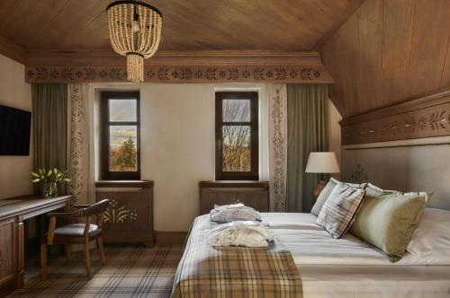 a bedroom with a bed and a desk and windows at Willa na Kozińcu Luxury Residence & SPA with Mountain View Zakopane in Zakopane