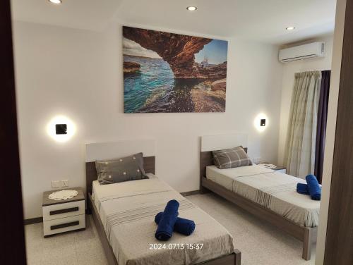 two beds in a room with blue pillows on them at Seafront 3 bed Panoramic SeaViews Apt B7- in Qbajjar