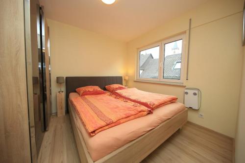 a bedroom with a bed with orange sheets and a window at Ferienwohnung Fine in Lorch am Rhein