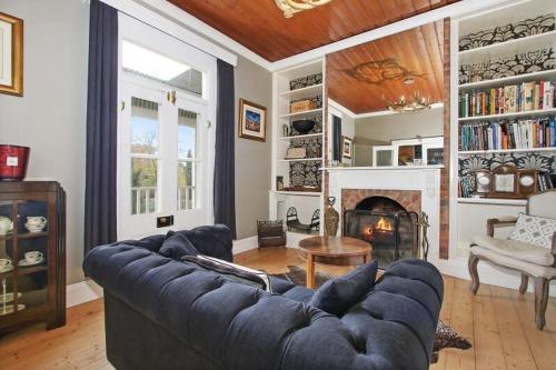 a living room with a blue couch and a fireplace at Malakoff House - Charm & Luxury in Beechworth