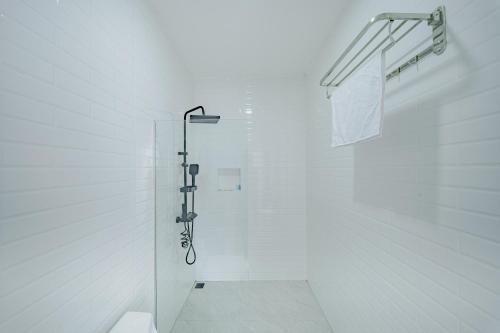 a white bathroom with a shower in a white wall at Ayodhya Villa Utari - North Wings in Yogyakarta