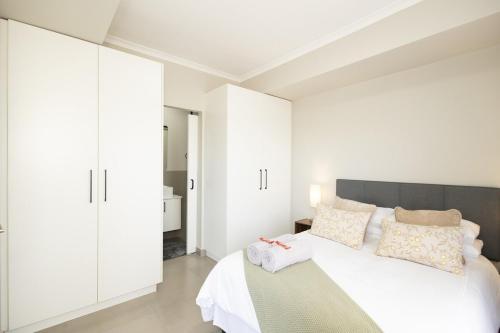a white bedroom with a bed and white cabinets at Durbanville Daydream in Durbanville