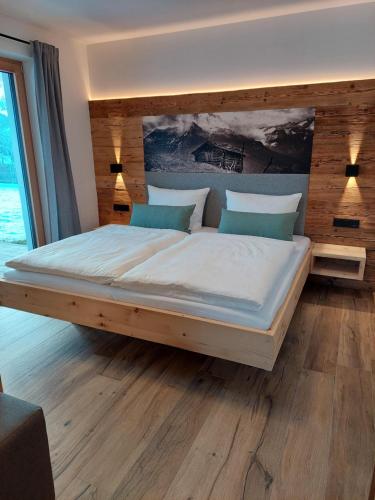 a bedroom with a large bed with a wooden headboard at Apart s'Peintl in Obertilliach