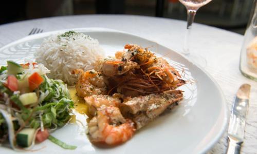 a plate of food with shrimp and rice on a table at Auberge d'Anse Boileau & Restaurant Chez Plume in Anse Boileau