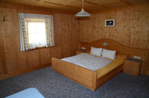 ein Schlafzimmer mit einem Bett in einem Holzzimmer in der Unterkunft Ferienwohnung Mitterwalder in Innervillgraten