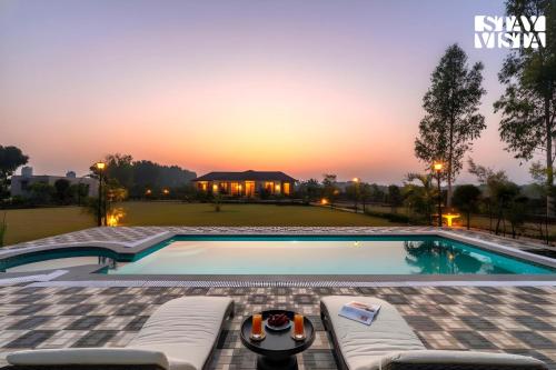 a swimming pool with a sunset in the background at StayVista at Treeansh with Pool, Lawn in Mohali