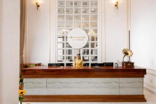 a woman standing behind a reception desk in a room at Mira Boutique Hotel Quy Nhon in Quy Nhon
