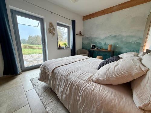 a bedroom with a large bed and a large window at Entre sabots et ronrons in Butten