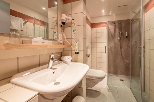a bathroom with a sink and a toilet and a shower at Golfhotel Fahrenbach in Tröstau