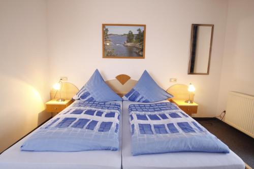 a bedroom with a bed with blue pillows at Hotel-Cafe Hanfstingl in Egling