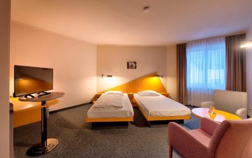 a hotel room with two beds and a tv at Golfhotel Fahrenbach in Tröstau