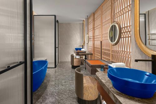 a bathroom with two blue sinks and a tub at 库尔勒绿发万丽酒店 in Korla