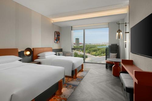 a hotel room with two beds and a large window at 库尔勒绿发万丽酒店 in Korla